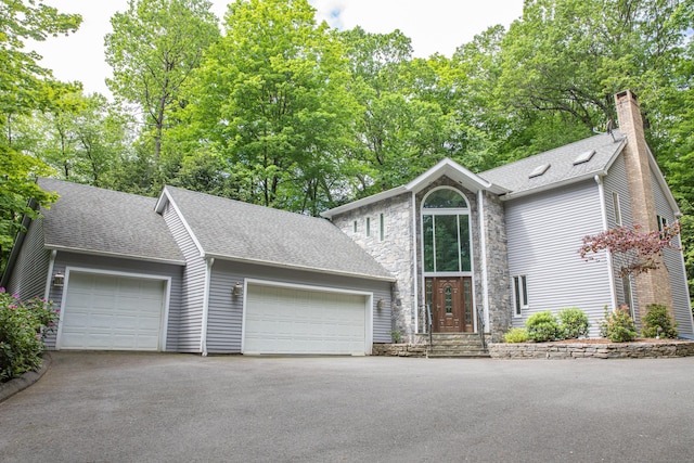 43 Metacomet Rd, Farmington, CT 06032 - view of front facade featuring roof with shingles, a garage, asphalt driveway, a chimney, and stone siding