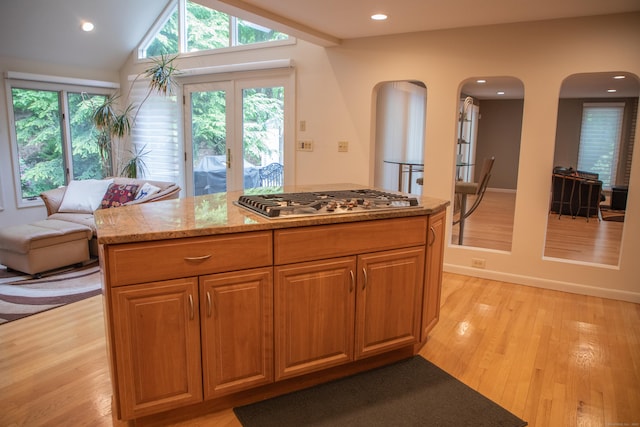 43 Metacomet Rd, Farmington, CT 06032 - kitchen featuring arched walkways, stainless steel gas stovetop, light wood-style floors, light stone counters, and a center island
