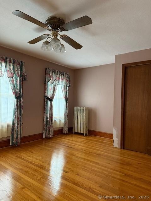 11 Deerfield St, East Haven, CT 06512 - empty room featuring radiator, light wood-type flooring, ceiling fan, and baseboards