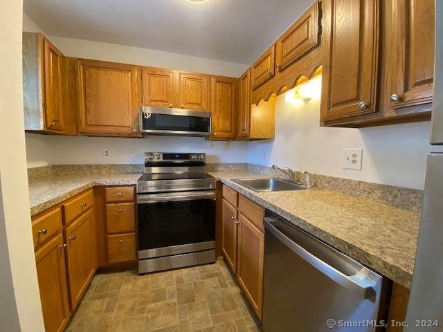 57 Senior Dr Unit 57, Monroe, CT 06468 - kitchen with appliances with stainless steel finishes, a sink, brown cabinetry, and light countertops
