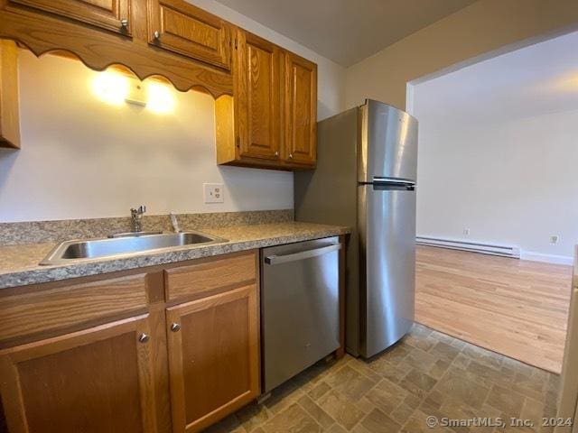 57 Senior Dr Unit 57, Monroe, CT 06468 - kitchen with appliances with stainless steel finishes, a baseboard radiator, a sink, brown cabinetry, and stone finish flooring