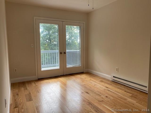 57 Senior Dr Unit 57, Monroe, CT 06468 - empty room with a baseboard heating unit, french doors, light wood finished floors, and baseboards