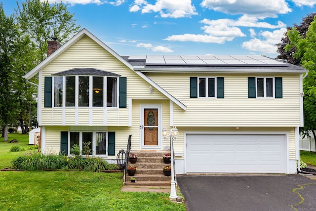 50 Marlene St, Bristol, CT 06010 - split foyer home featuring an attached garage, solar panels, asphalt driveway, a front lawn, and a chimney