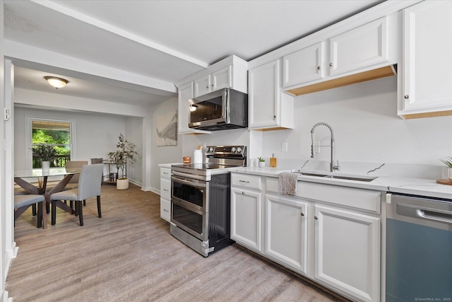 34 Pleasant St Unit 6, Plainfield, CT 06374 - kitchen featuring stainless steel appliances, a sink, light wood-style floors, white cabinets, and light stone counters