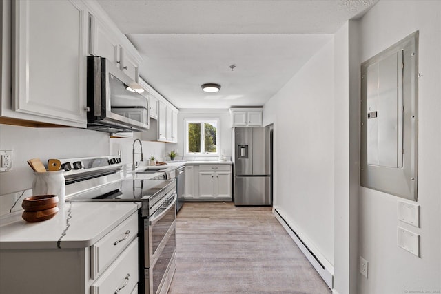 34 Pleasant St Unit 6, Plainfield, CT 06374 - kitchen with stainless steel appliances, a baseboard radiator, electric panel, a sink, and light wood finished floors