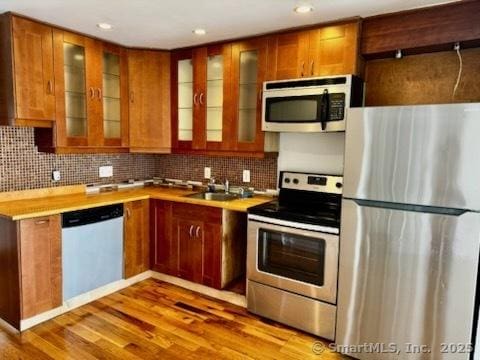 133 Main St Apt 4, Norwalk, CT 06851 - kitchen featuring appliances with stainless steel finishes, light countertops, tasteful backsplash, glass insert cabinets, and recessed lighting