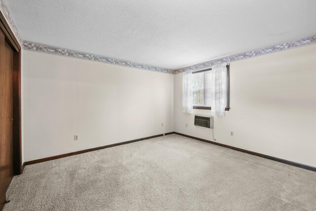 415 Lady Bug Ln Unit 415, Vernon, CT 06066 - unfurnished bedroom with light carpet, baseboards, a textured ceiling, a closet, and a wall mounted AC