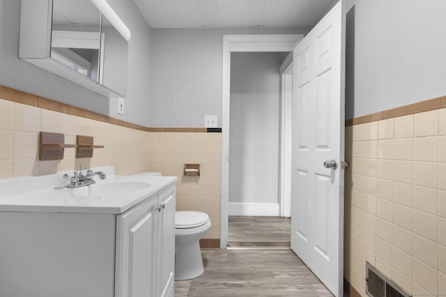 108 Highland Ave, Waterbury, CT 06708 - half bath featuring tile walls, vanity, toilet, a wainscoted wall, and wood finished floors