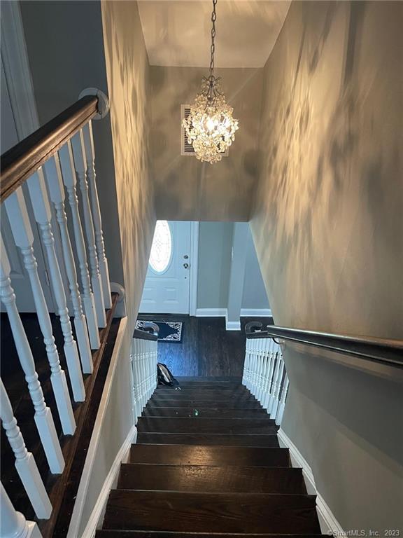 665 W Main St, West Haven, CT 06516 - stairway featuring a chandelier, baseboards, and wood finished floors