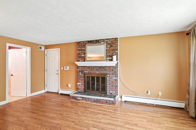 5 Crabapple Rd, Windsor, CT 06095 - unfurnished living room with wood finished floors, a baseboard heating unit, a brick fireplace, baseboards, and a textured ceiling