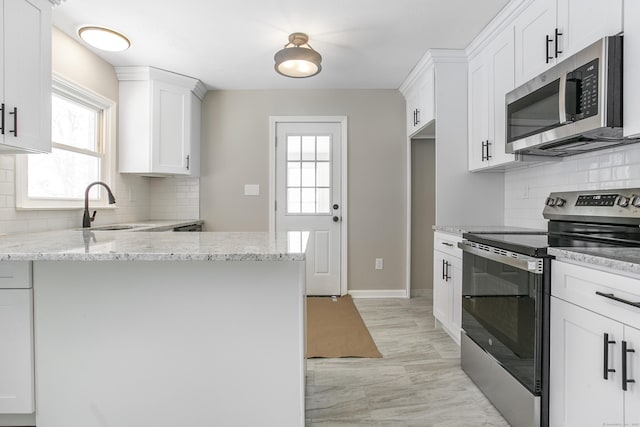 24 Manning St, New Fairfield, CT 06812 - kitchen featuring stainless steel appliances, a sink, a peninsula, light stone counters, and white cabinetry