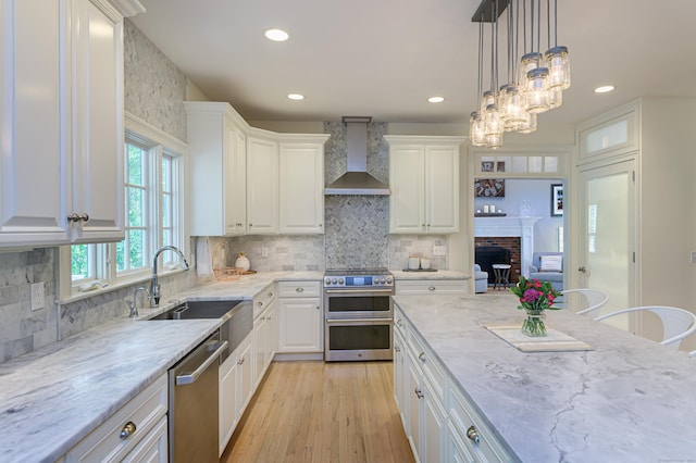 68 Topstone Rd, Ridgefield, CT 06877 - kitchen featuring wall chimney exhaust hood, stainless steel appliances, a brick fireplace, white cabinetry, and recessed lighting