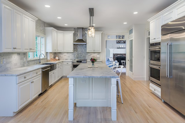 68 Topstone Rd, Ridgefield, CT 06877 - kitchen with stainless steel appliances, wall chimney exhaust hood, a sink, white cabinets, and a kitchen island