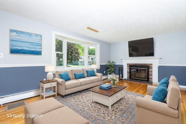 10 Cartier Rd, Enfield, CT 06082 - living area with wood finished floors, baseboard heating, a brick fireplace, and baseboards