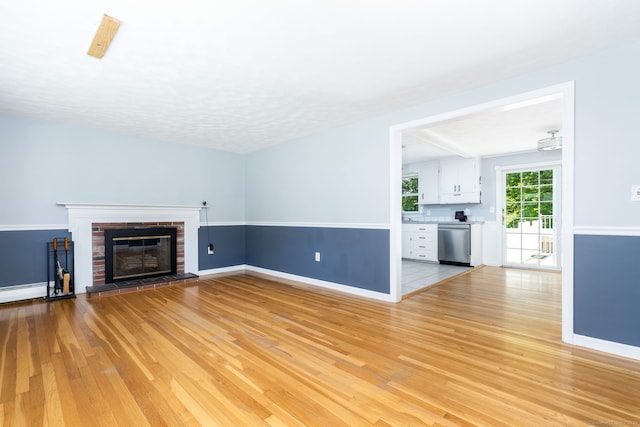 10 Cartier Rd, Enfield, CT 06082 - unfurnished living room featuring light wood-type flooring, baseboards, and a brick fireplace