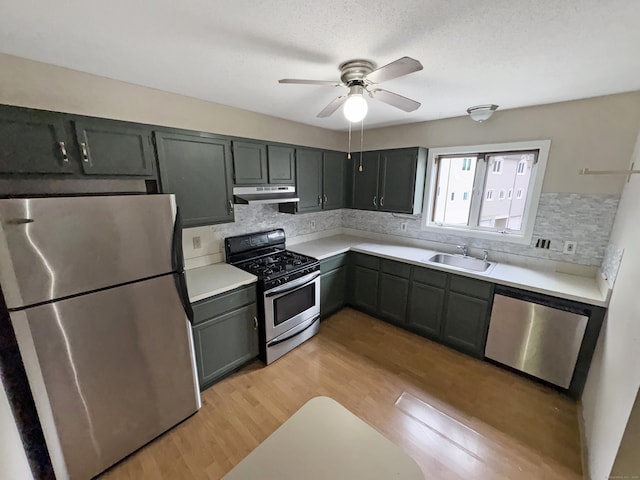 245 E Woodland St Apt 14, Meriden, CT 06451 - kitchen featuring appliances with stainless steel finishes, under cabinet range hood, a sink, decorative backsplash, and light wood-type flooring
