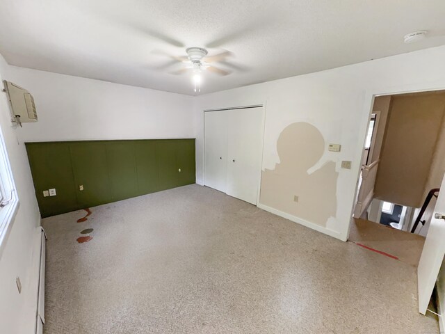 245 E Woodland St Apt 14, Meriden, CT 06451 - unfurnished bedroom featuring baseboard heating, a closet, ceiling fan, carpet, and a wall mounted AC