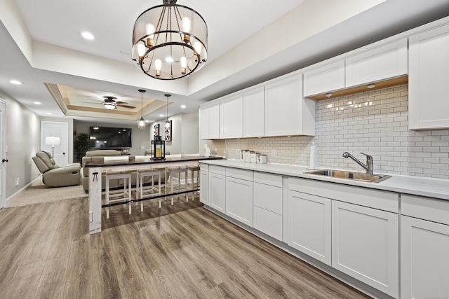 81 Aresco Dr, Middletown, CT 06457 - kitchen featuring a sink, open floor plan, a tray ceiling, a ceiling fan, and wood finished floors