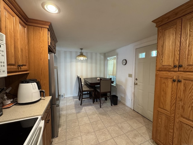87 Munson Rd, Beacon Falls, CT 06403 - kitchen with brown cabinets, freestanding refrigerator, light countertops, wallpapered walls, and baseboards