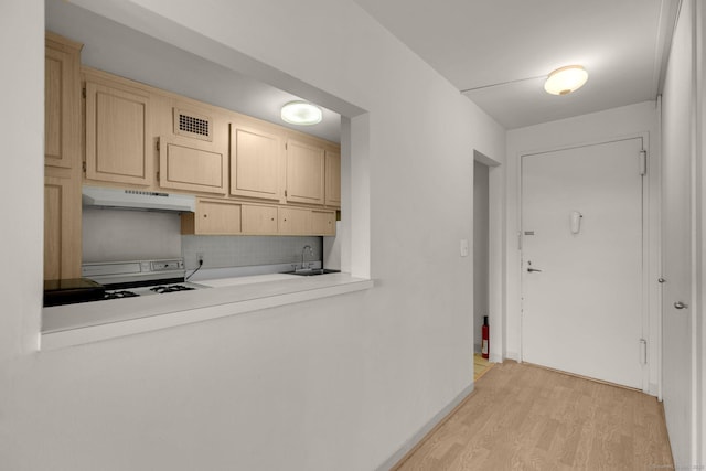 2625 Park Ave Unit 7R, Bridgeport, CT 06604 - kitchen with light brown cabinetry, under cabinet range hood, light wood finished floors, decorative backsplash, and light countertops