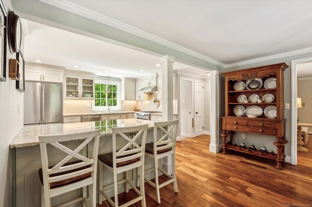 8 Buttonwood Dr, Simsbury, CT 06070 - kitchen featuring appliances with stainless steel finishes, light stone countertops, a kitchen breakfast bar, a peninsula, and backsplash