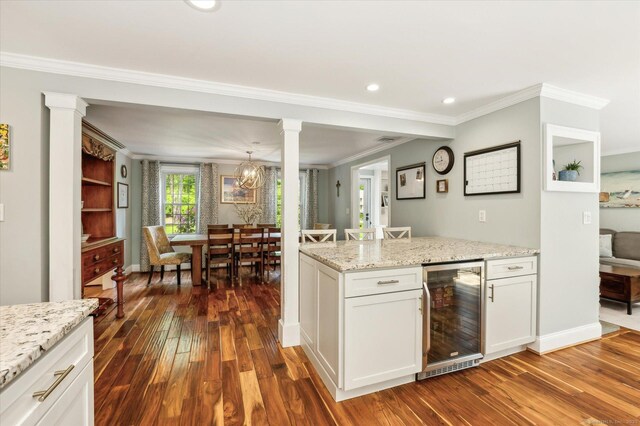 8 Buttonwood Dr, Simsbury, CT 06070 - kitchen featuring wine cooler, dark wood-type flooring, crown molding, white cabinetry, and decorative columns