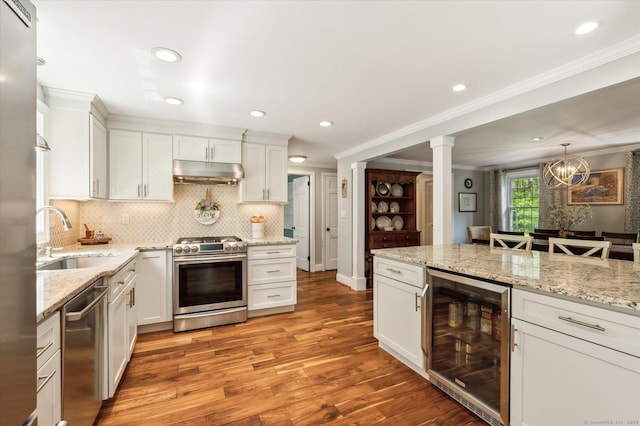 8 Buttonwood Dr, Simsbury, CT 06070 - kitchen featuring appliances with stainless steel finishes, wine cooler, under cabinet range hood, tasteful backsplash, and crown molding