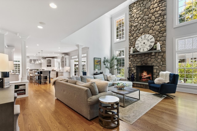 249 Sturges Hwy, Westport, CT 06880 - living area with decorative columns, wood finished floors, a stone fireplace, a towering ceiling, and recessed lighting