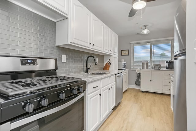 87 E Broadway Unit D, Milford, CT 06460 - kitchen with range with gas stovetop, a sink, stainless steel dishwasher, white cabinetry, and backsplash