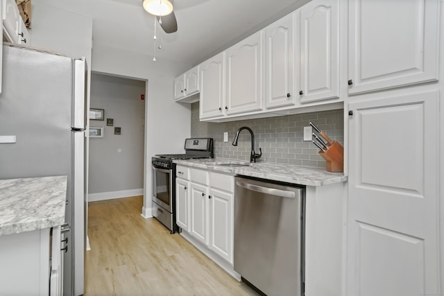 87 E Broadway Unit D, Milford, CT 06460 - kitchen with stainless steel appliances, a sink, backsplash, baseboards, and white cabinetry