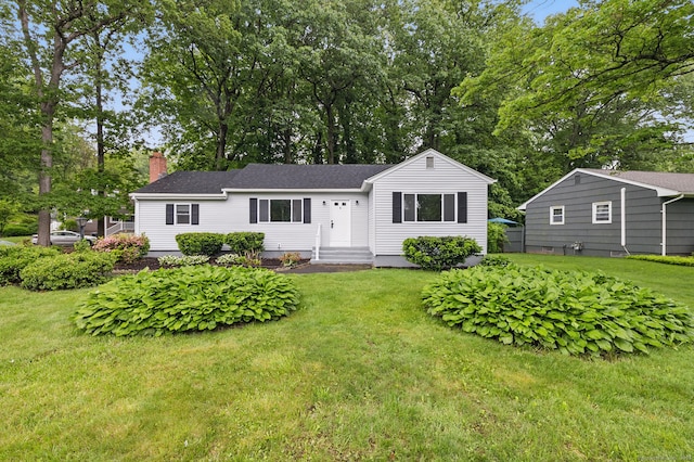 single story home with a chimney, a front yard, and view of scattered trees