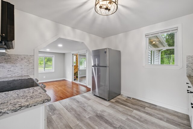 kitchen featuring freestanding refrigerator, light wood finished floors, range, baseboards, and a chandelier