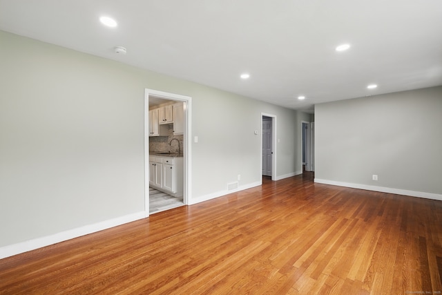 spare room with a sink, recessed lighting, light wood-type flooring, a smoke detector, and baseboards