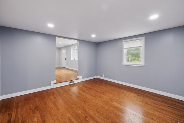 empty room featuring wood finished floors, baseboards, recessed lighting, and plenty of natural light