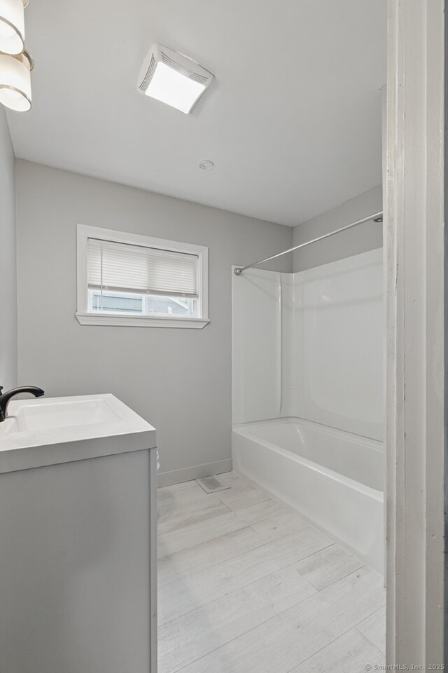 bathroom with  shower combination, vanity, baseboards, and wood finished floors