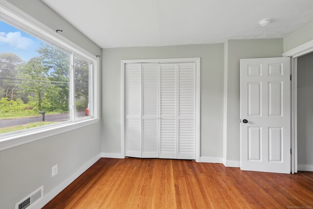 unfurnished bedroom with baseboards, wood finished floors, and a closet