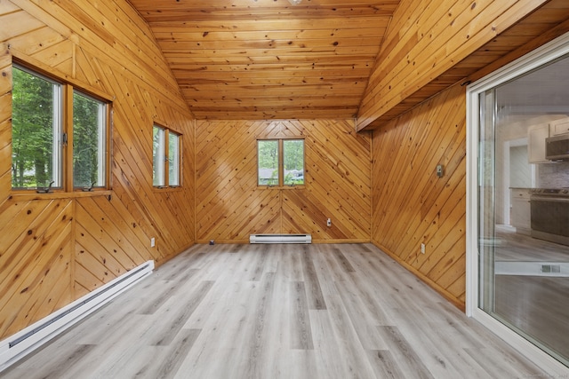 spare room featuring a baseboard heating unit, healthy amount of natural light, lofted ceiling, light wood finished floors, and wooden walls