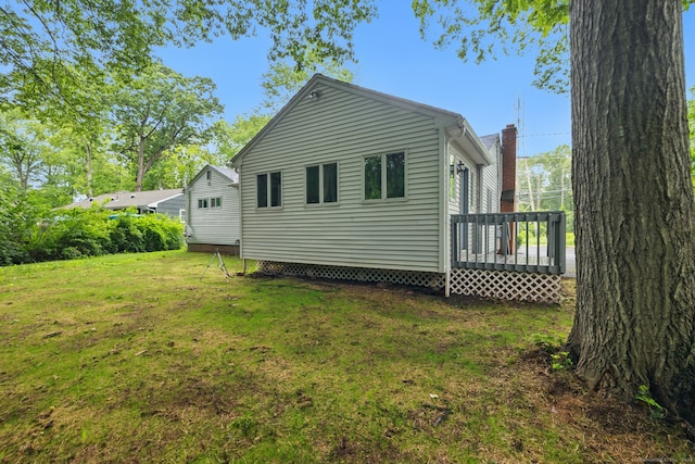 back of property with a lawn, a deck, and a chimney