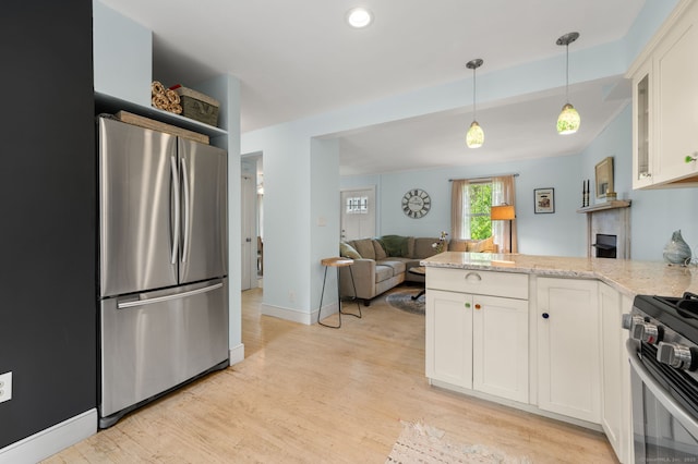 8 Maple Ave, Clinton, CT 06413 - kitchen featuring stainless steel appliances, a peninsula, white cabinets, light wood finished floors, and decorative light fixtures