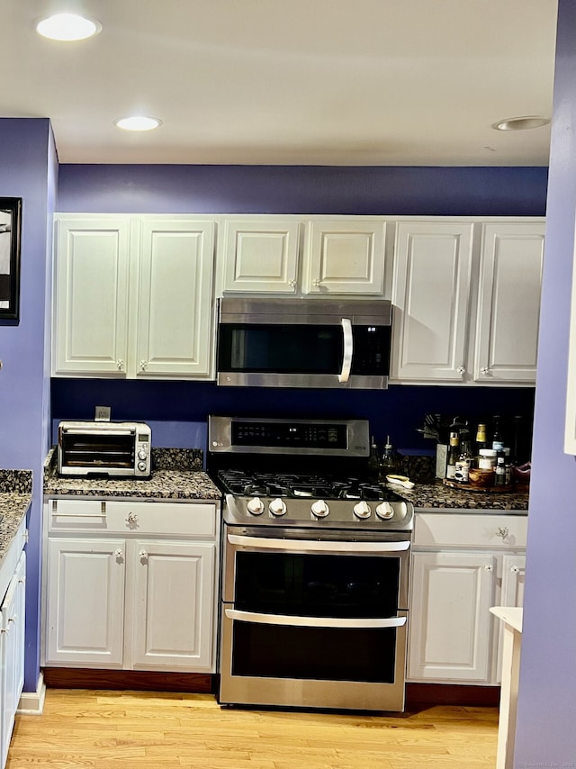 1006 Sienna Dr Unit 1006, Danbury, CT 06810 - kitchen featuring stainless steel appliances, white cabinetry, light wood-style floors, dark stone countertops, and recessed lighting