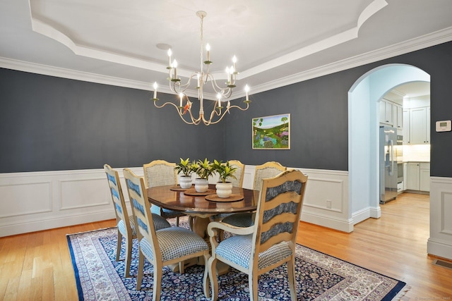 36 Fox Mdw, Marlborough, CT 06447 - dining room featuring a tray ceiling, light wood-style flooring, arched walkways, a chandelier, and a wainscoted wall