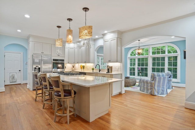 36 Fox Mdw, Marlborough, CT 06447 - kitchen with appliances with stainless steel finishes, arched walkways, a center island, light wood-style floors, and backsplash