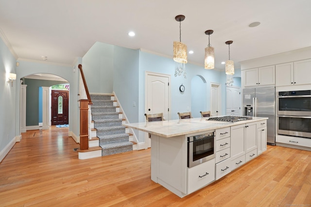 36 Fox Mdw, Marlborough, CT 06447 - kitchen with arched walkways, stainless steel appliances, ornamental molding, white cabinets, and light wood finished floors