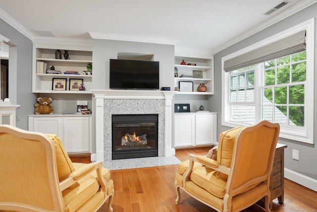 36 Fox Mdw, Marlborough, CT 06447 - living area with a fireplace with flush hearth, wood finished floors, crown molding, and built in shelves