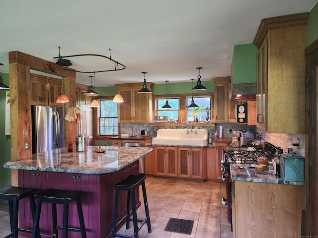310 S Bigelow Rd, Hampton, CT 06247 - kitchen with appliances with stainless steel finishes, brown cabinetry, tasteful backsplash, a breakfast bar, and dark stone countertops