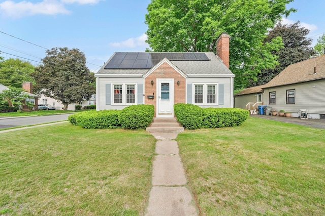 151 Mckee St, Manchester, CT 06040 - bungalow-style house featuring solar panels, a front yard, a chimney, and brick siding