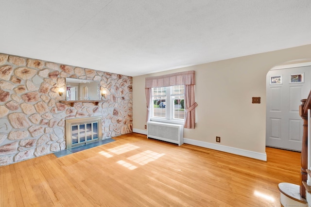 151 Mckee St, Manchester, CT 06040 - unfurnished living room featuring radiator heating unit, wood finished floors, a fireplace, and arched walkways