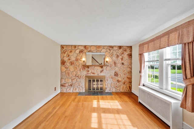 151 Mckee St, Manchester, CT 06040 - unfurnished living room featuring radiator heating unit, a stone fireplace, wood finished floors, and baseboards