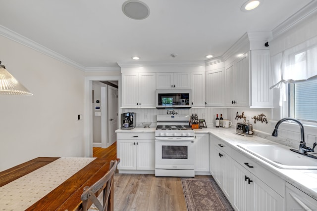 1 Freedman Dr, Norwalk, CT 06854 - kitchen featuring white appliances, a sink, white cabinetry, ornamental molding, and light wood-style flooring