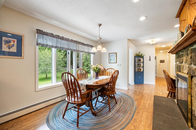176 Prospect Hill Rd, Colchester, CT 06415 - dining area featuring a textured ceiling, plenty of natural light, a fireplace, baseboard heating, and light wood-style floors